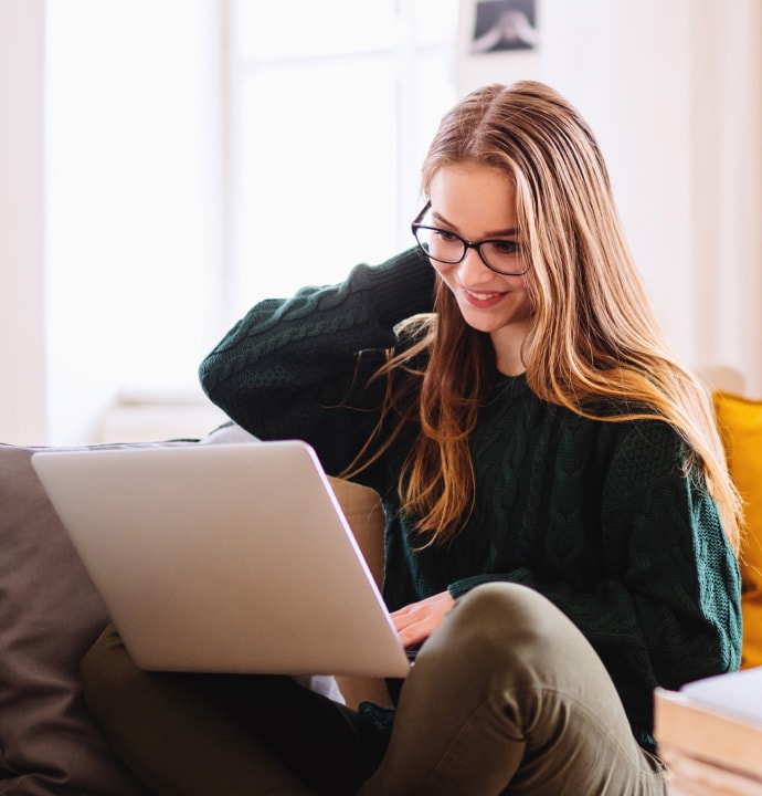 pige på sofa med bærbar computer, der starter Norton 360 Standard op.