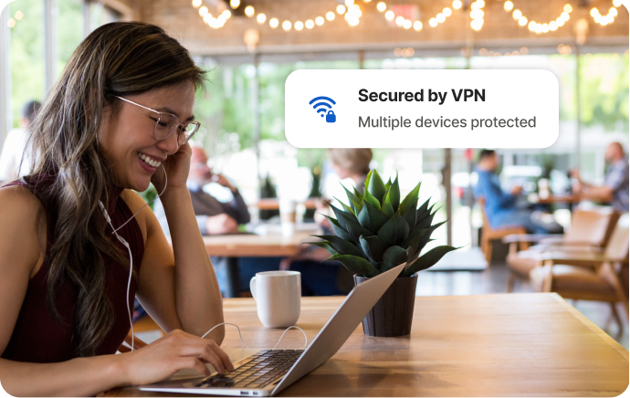 Kvinde på en café griner på en skærm på en bærbar computer