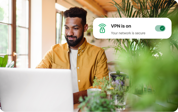 Mand omgivet af planter smiler til en bærbar computer